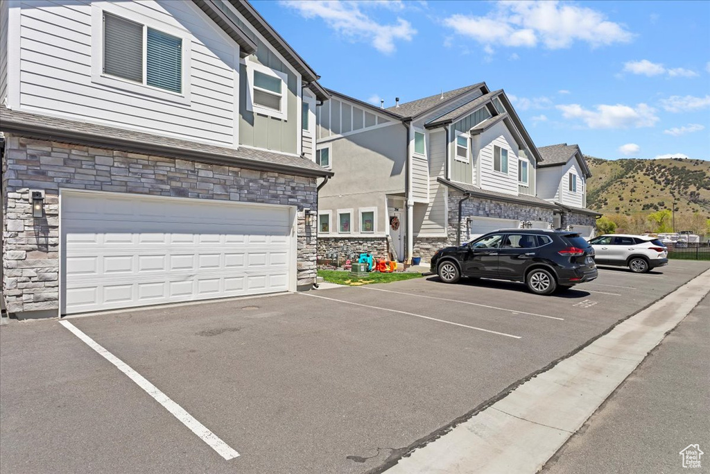 View of front facade featuring stone siding, uncovered parking, a mountain view, and board and batten siding