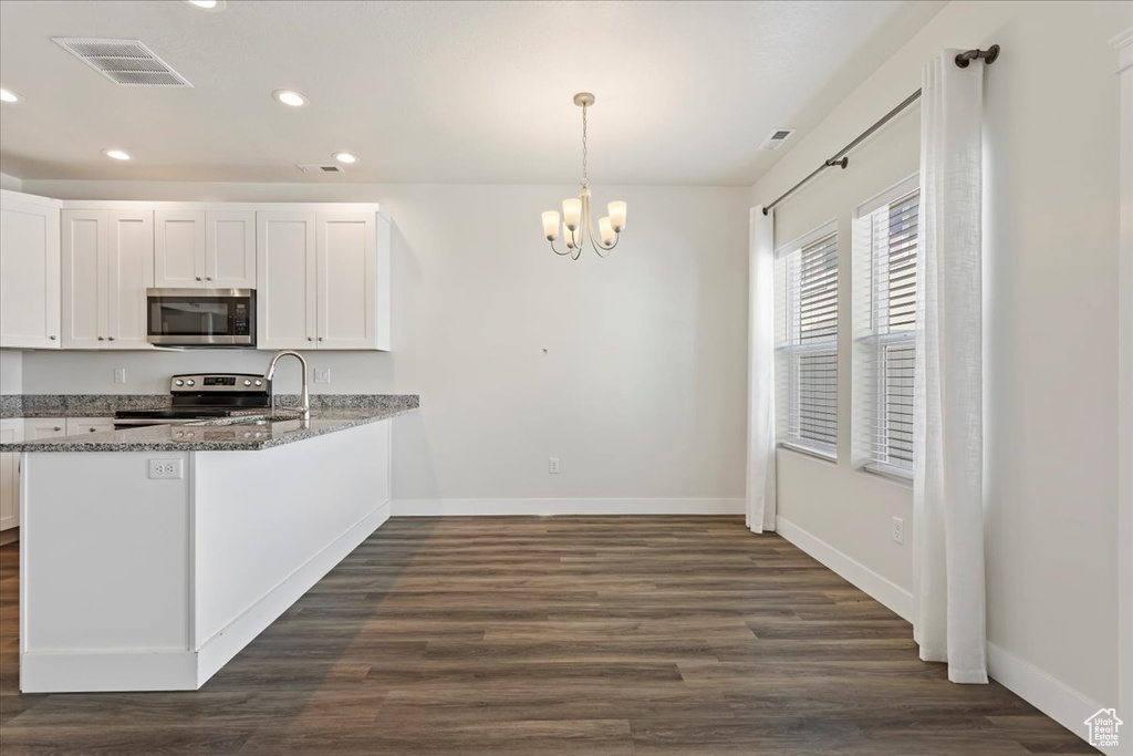 Kitchen with stainless steel appliances, baseboards, recessed lighting, a chandelier, and dark wood finished floors