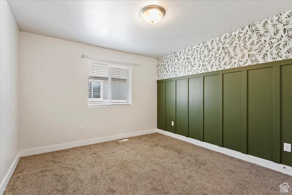 Carpeted empty room with baseboards and wallpapered walls