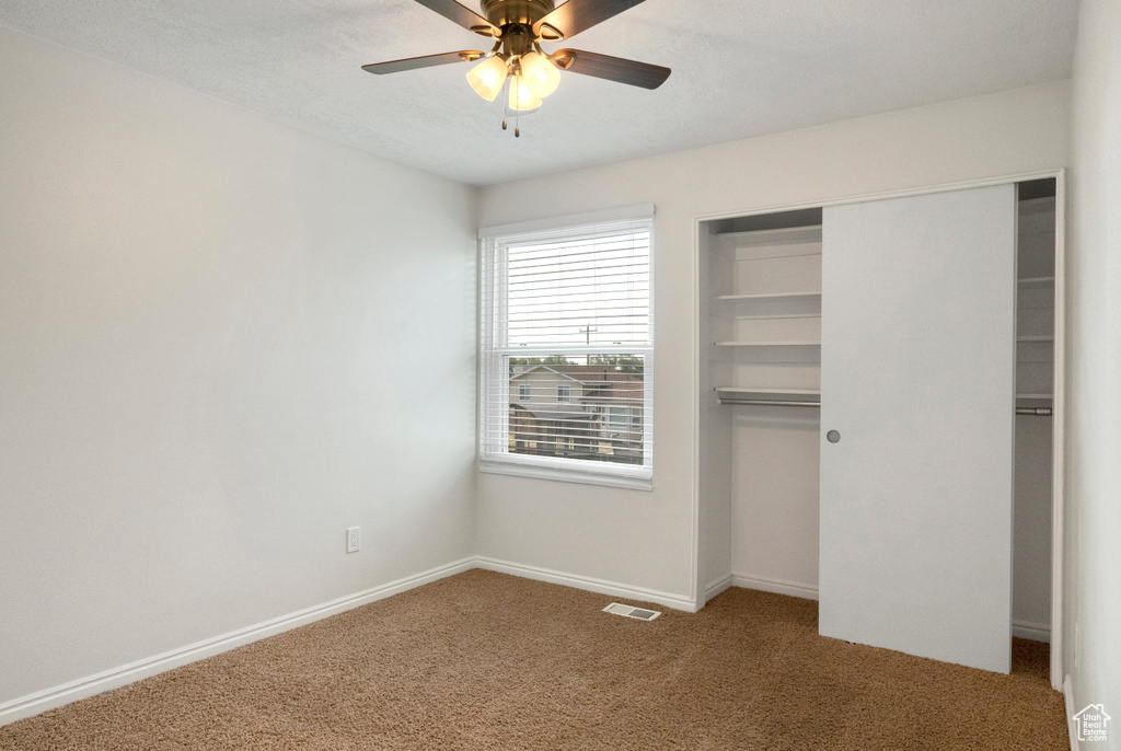 Unfurnished bedroom featuring carpet floors, a closet, baseboards, and ceiling fan