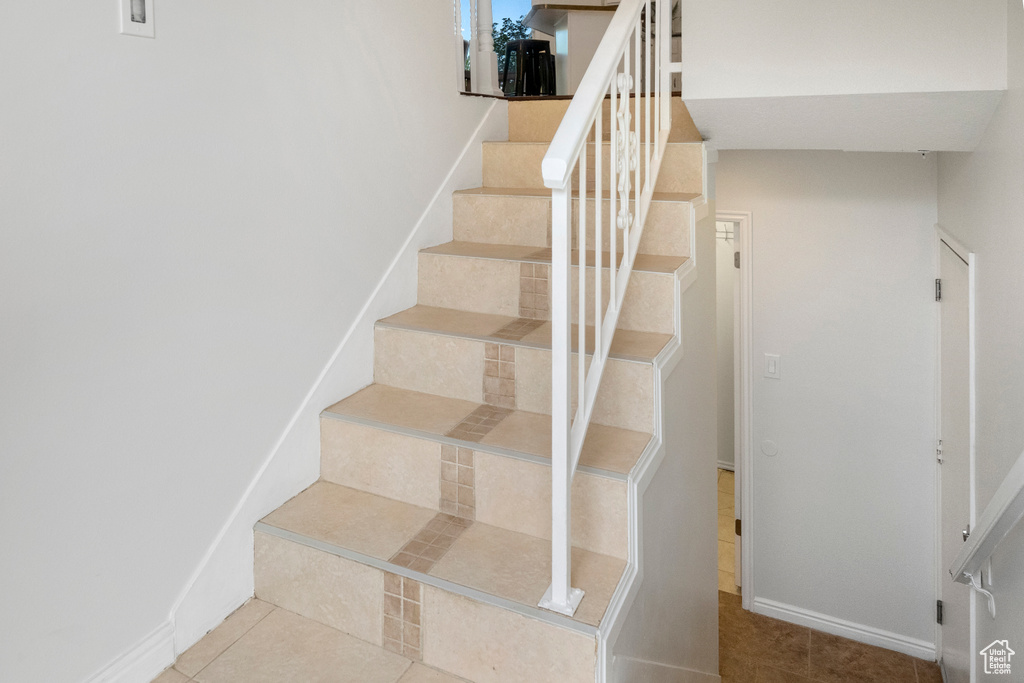 Staircase featuring tile patterned flooring and baseboards