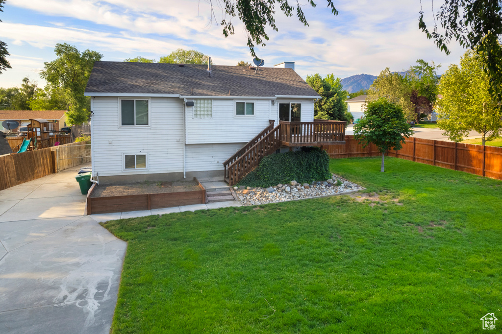 Rear view of property featuring a deck with mountain view, a shingled roof, a chimney, and stairway
