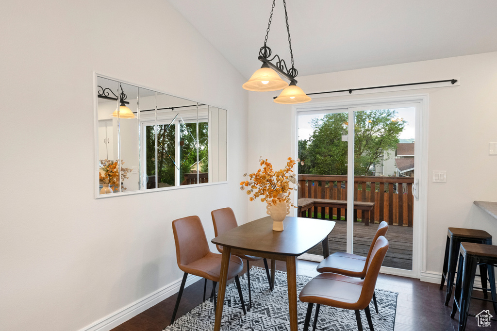 Dining space featuring dark wood finished floors, baseboards, and lofted ceiling
