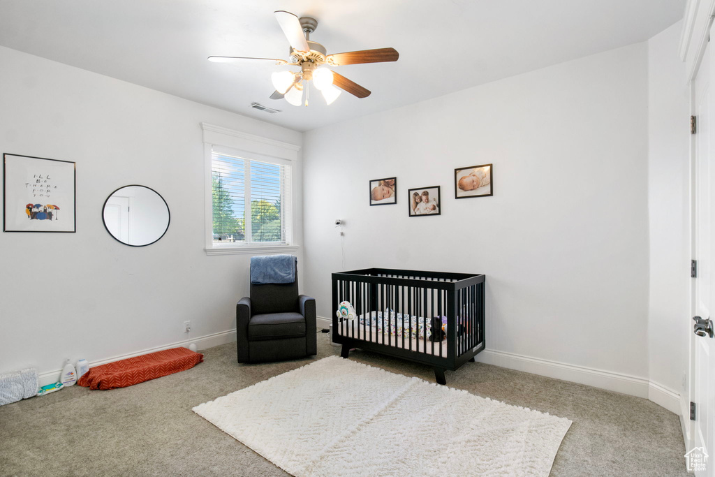 Carpeted bedroom with baseboards, a ceiling fan, and a nursery area