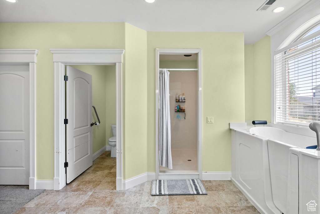 Bathroom featuring a stall shower, toilet, a bath, baseboards, and recessed lighting