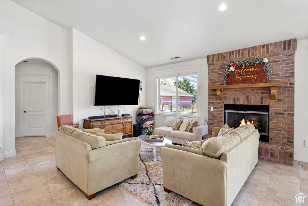 Living room with arched walkways, recessed lighting, a fireplace, lofted ceiling, and baseboards