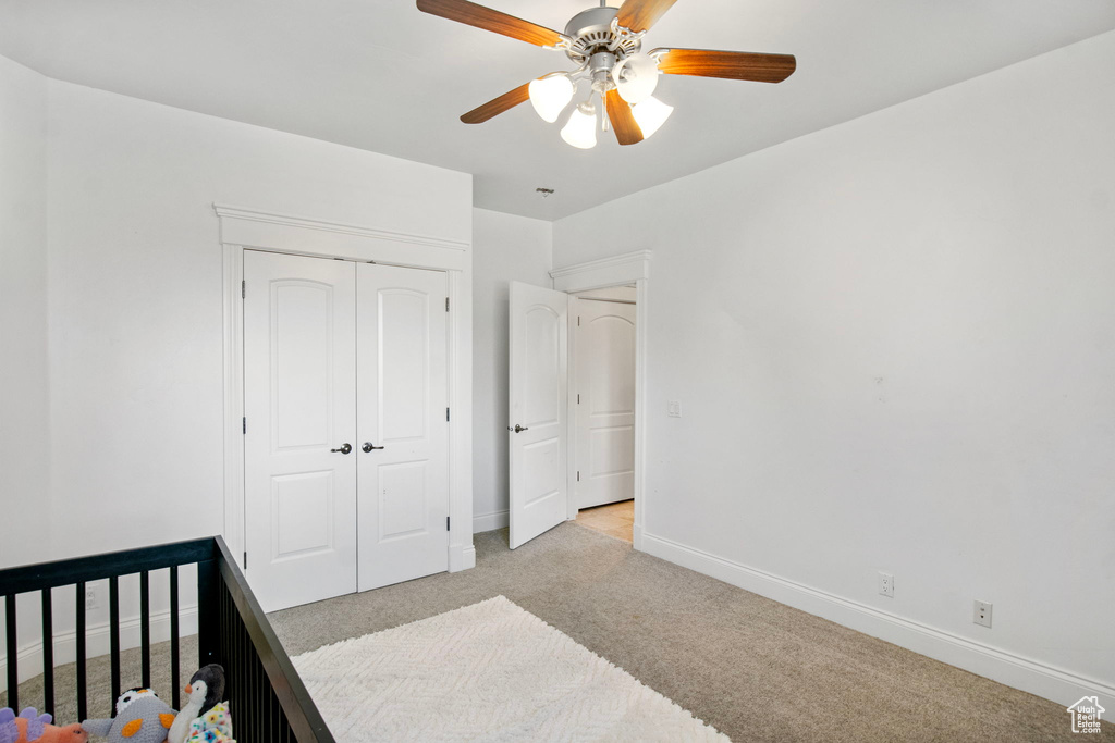 Unfurnished bedroom featuring light carpet, baseboards, a closet, and ceiling fan
