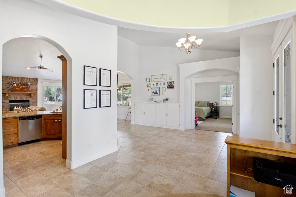 Entrance foyer featuring arched walkways, a fireplace, a ceiling fan, a chandelier, and baseboards