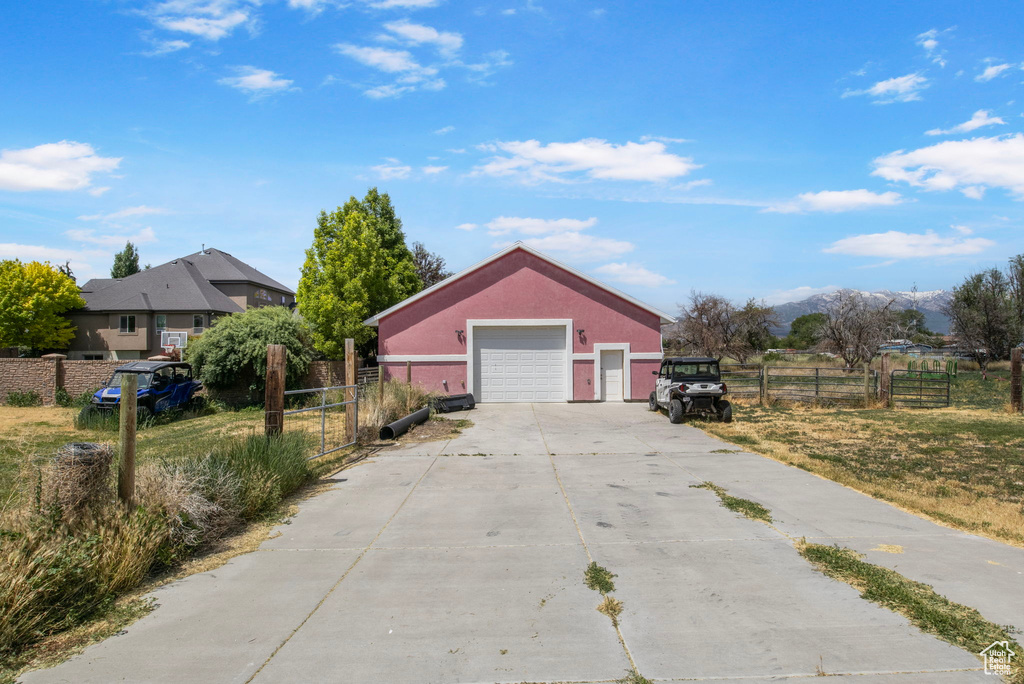 View of front of property featuring concrete driveway, a detached garage, an outdoor structure, a mountain view, and stucco siding