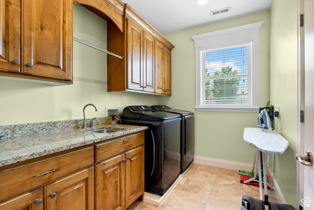 Laundry area with cabinet space, washing machine and dryer, baseboards, and light tile patterned floors