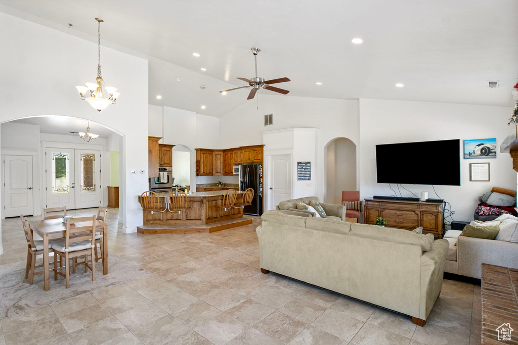 Living room with arched walkways, a ceiling fan, recessed lighting, a chandelier, and high vaulted ceiling