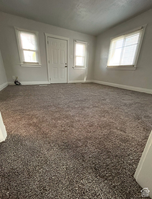 Carpeted spare room featuring baseboards and a textured ceiling