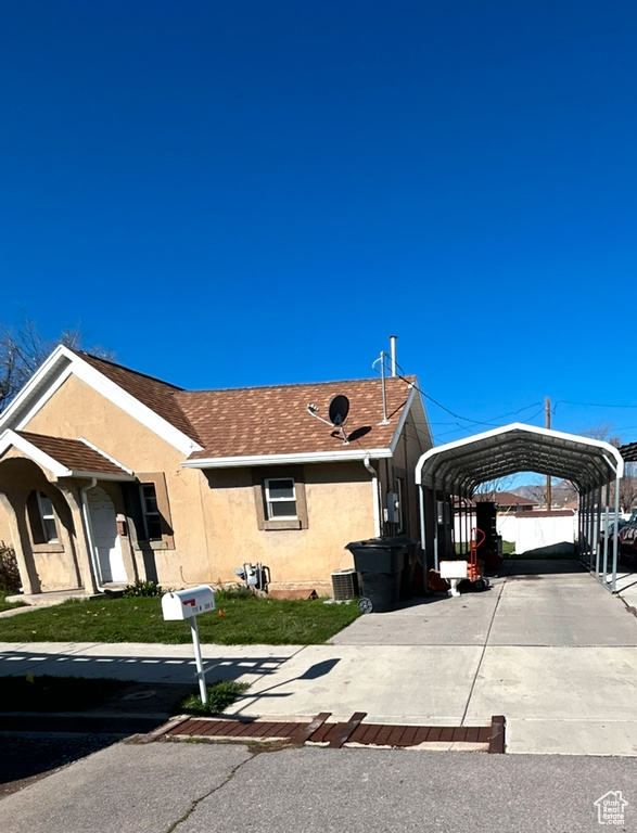 Single story home featuring stucco siding, a detached carport, concrete driveway, and roof with shingles
