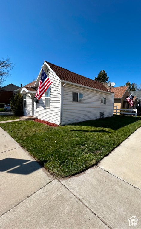 View of property exterior with a yard and roof with shingles