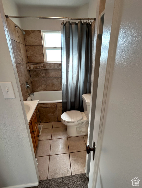 Bathroom featuring toilet, tiled shower / bath, tile patterned flooring, and vanity