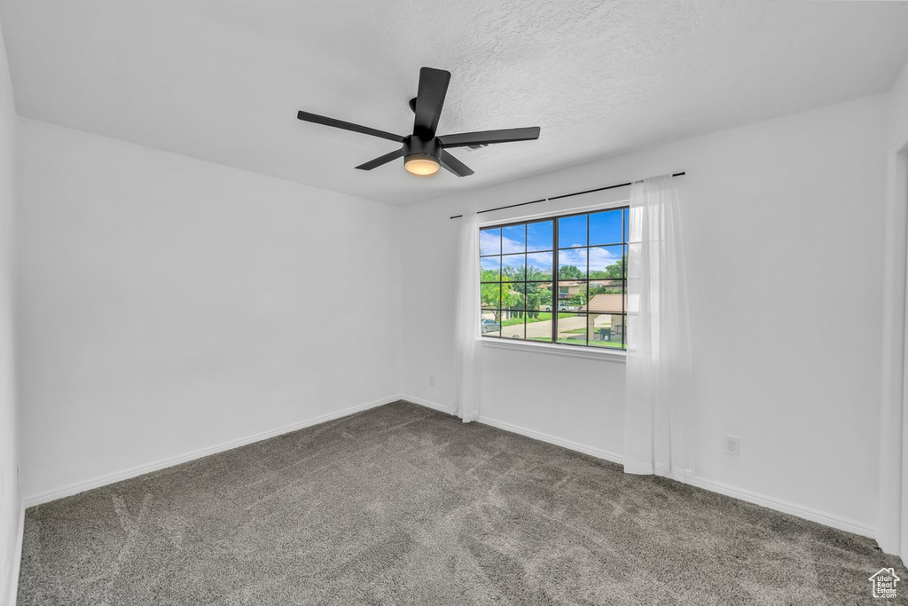 Carpeted empty room featuring ceiling fan, baseboards, and a textured ceiling