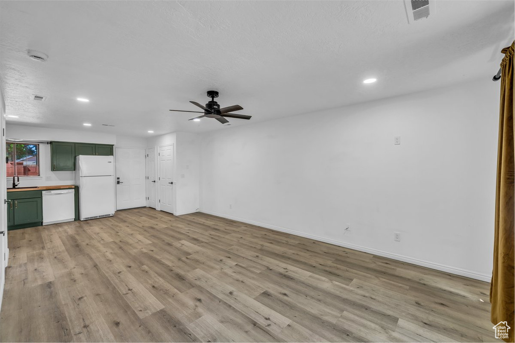 Unfurnished living room featuring recessed lighting, a ceiling fan, light wood-style flooring, baseboards, and a sink