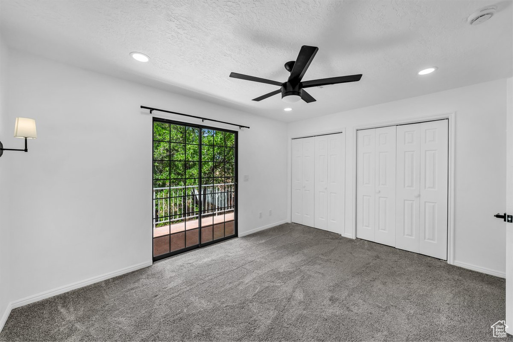 Unfurnished bedroom with access to exterior, two closets, baseboards, recessed lighting, and a textured ceiling