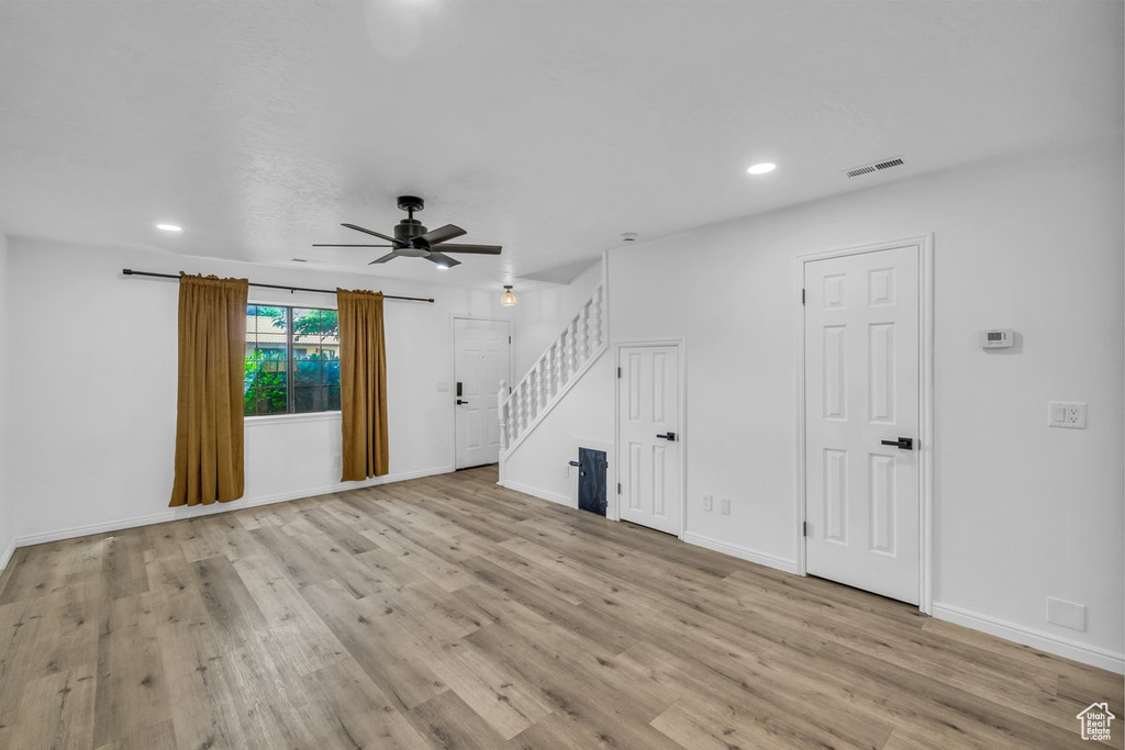 Unfurnished living room with stairway, ceiling fan, wood finished floors, recessed lighting, and baseboards