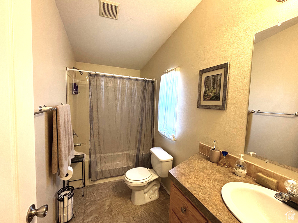 Bathroom with vanity, vaulted ceiling, toilet, and shower / bath combination with curtain