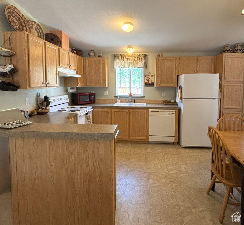 Kitchen featuring white appliances, under cabinet range hood, a sink, light flooring, and a peninsula