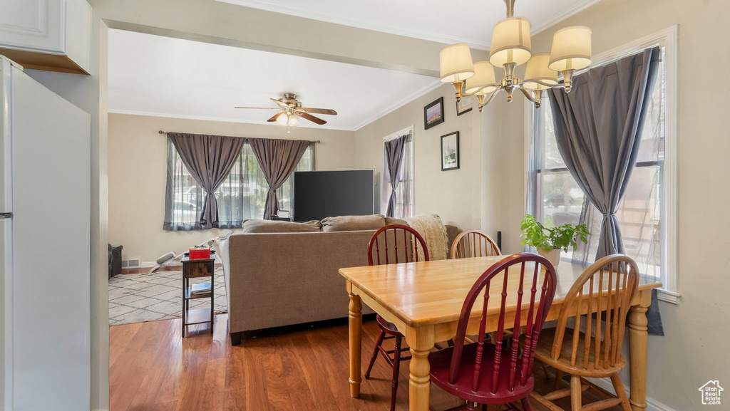 Dining space featuring a chandelier, crown molding, healthy amount of natural light, wood finished floors, and a ceiling fan