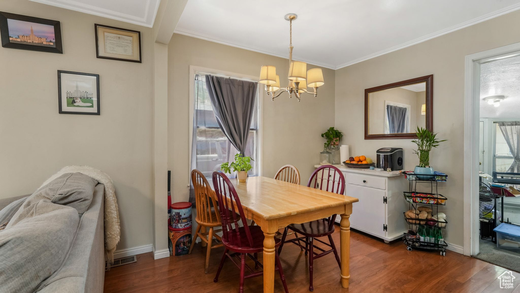 Dining room featuring a chandelier, wood finished floors, ornamental molding, healthy amount of natural light, and baseboards