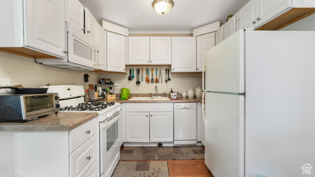 Kitchen with white appliances, white cabinetry, and a sink
