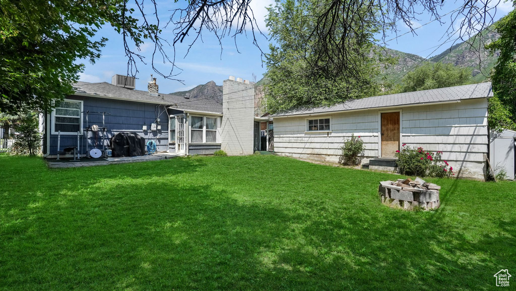 Rear view of property with a lawn, a fire pit, and a chimney