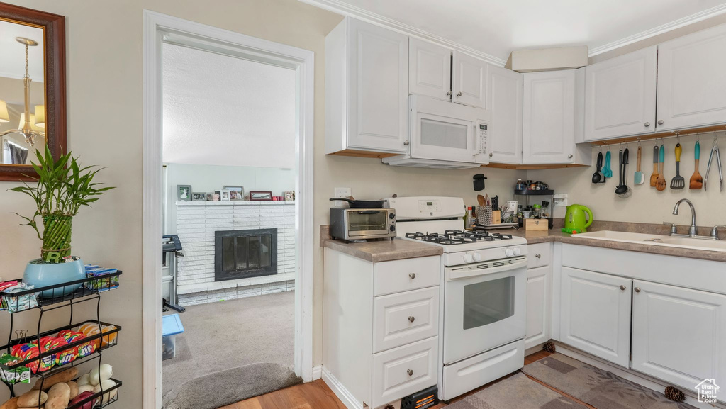 Kitchen featuring white appliances, a sink, and white cabinetry