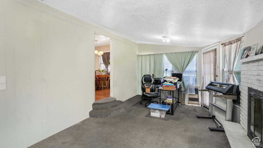 Workout room featuring carpet, healthy amount of natural light, a textured ceiling, a brick fireplace, and a chandelier
