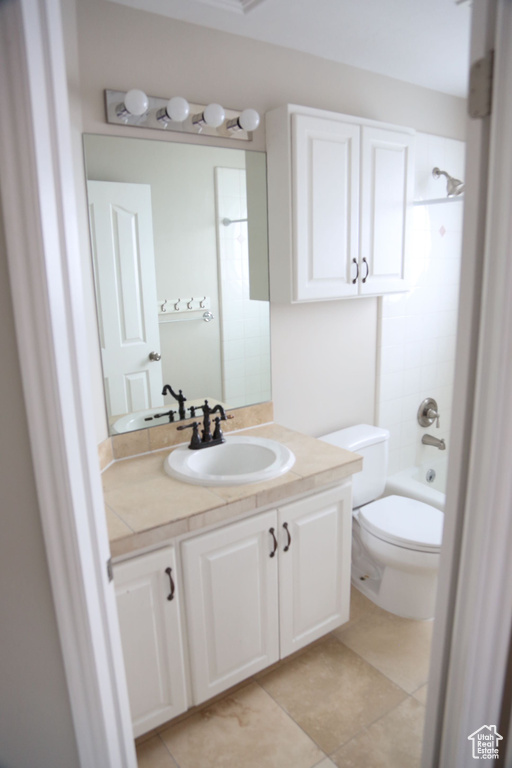 Bathroom featuring vanity, toilet, tile patterned floors, and washtub / shower combination