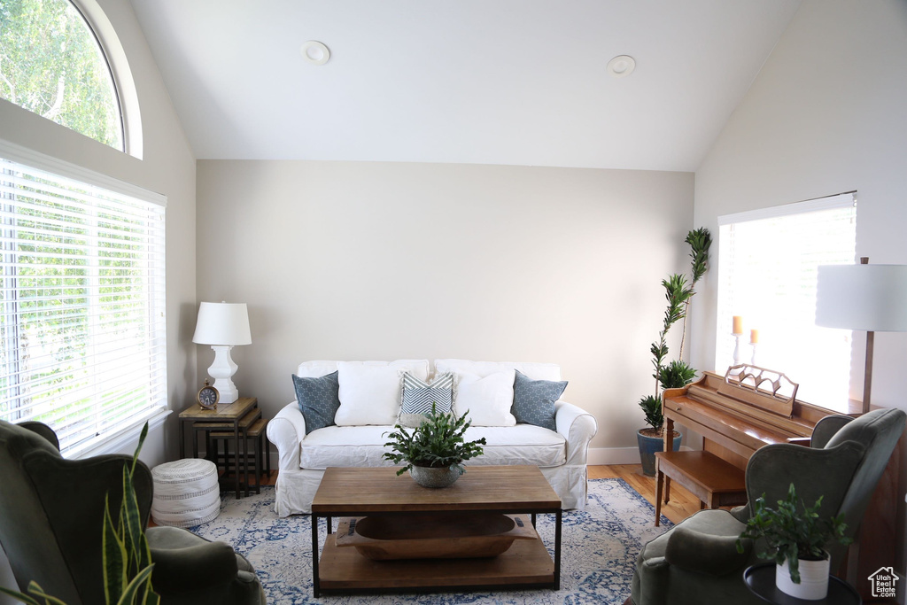 Living room with healthy amount of natural light, high vaulted ceiling, light wood finished floors, recessed lighting, and baseboards