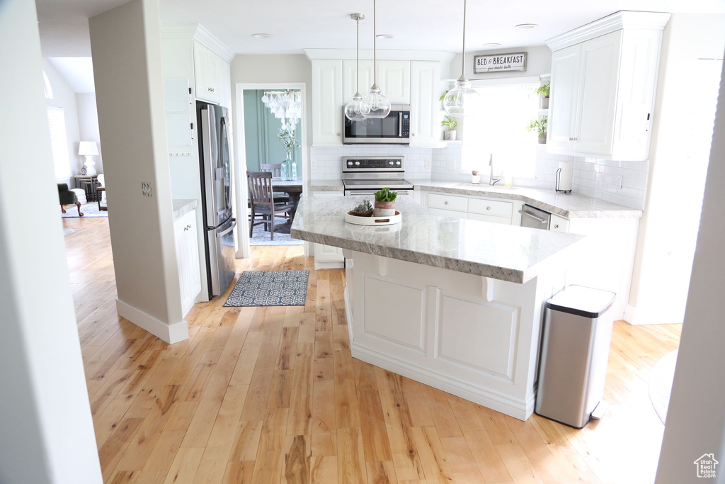 Kitchen featuring appliances with stainless steel finishes, plenty of natural light, white cabinetry, and tasteful backsplash