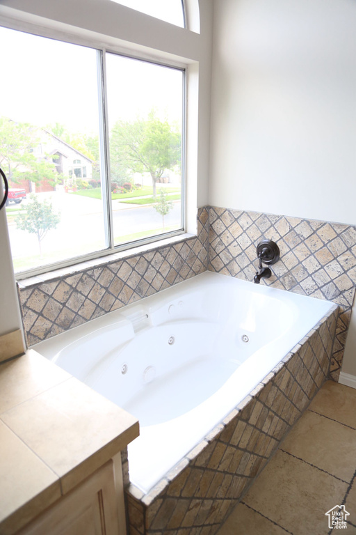 Full bathroom featuring plenty of natural light, a whirlpool tub, and tile patterned flooring