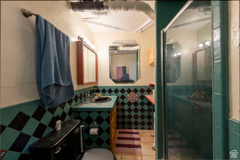 Bathroom with tile walls, wainscoting, a stall shower, vanity, and tile patterned flooring