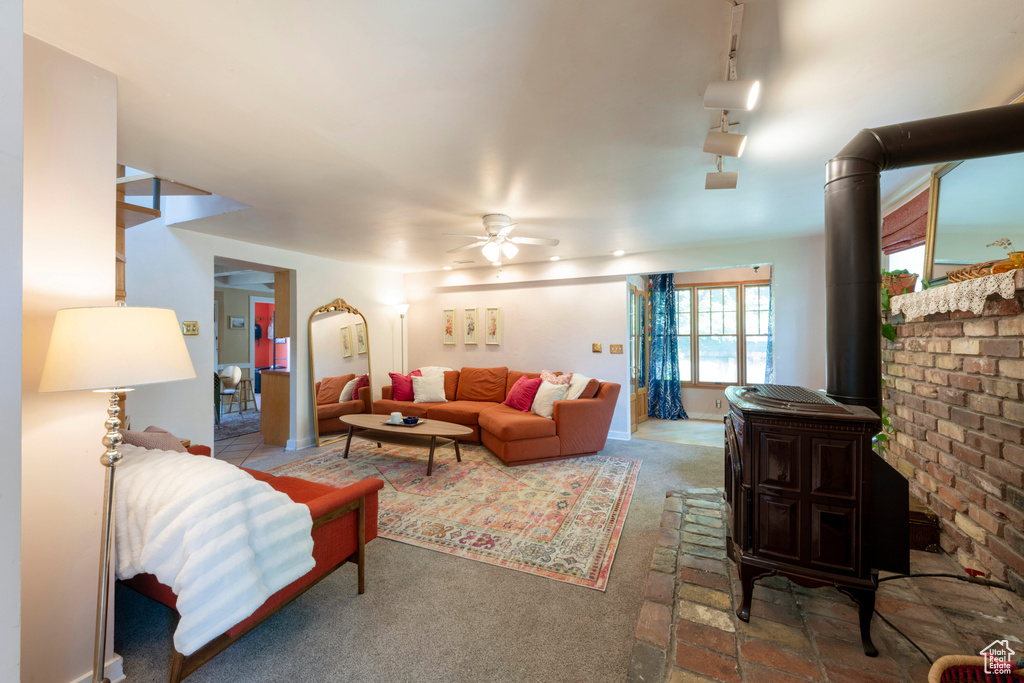 Carpeted living area featuring a wood stove and ceiling fan
