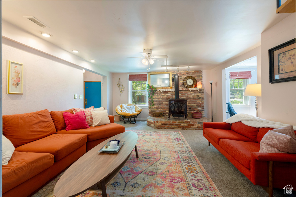 Carpeted living area with a wood stove, healthy amount of natural light, a ceiling fan, and track lighting