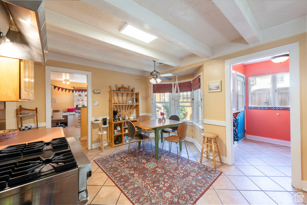 Dining space with beamed ceiling, light tile patterned flooring, baseboards, and ceiling fan