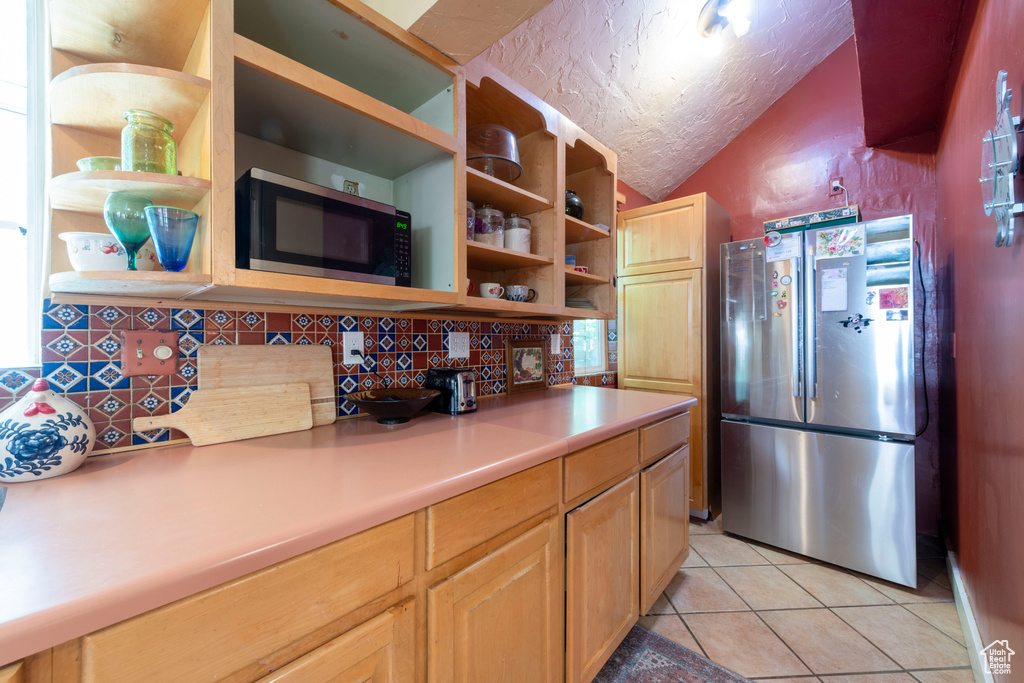 Kitchen with appliances with stainless steel finishes, open shelves, backsplash, light tile patterned floors, and light countertops