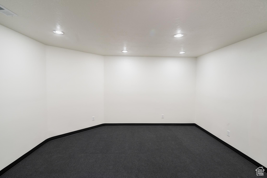 Empty room featuring recessed lighting, dark carpet, and baseboards