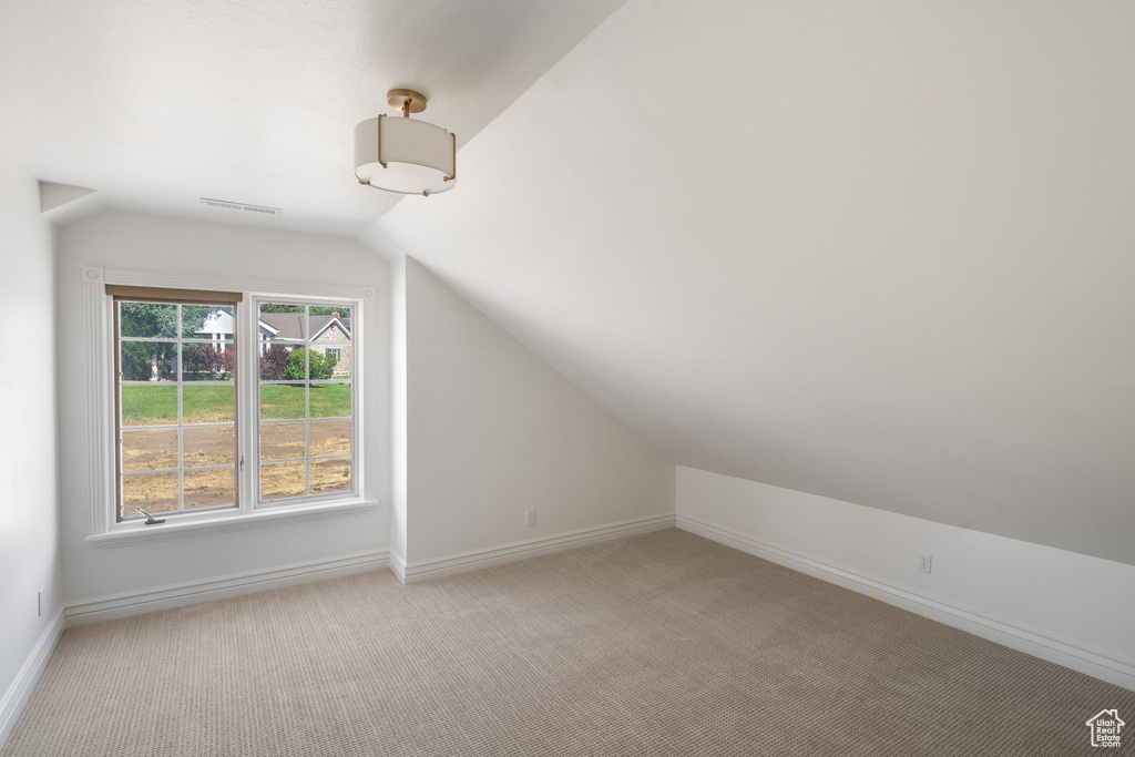 Bonus room featuring vaulted ceiling, light colored carpet, and baseboards