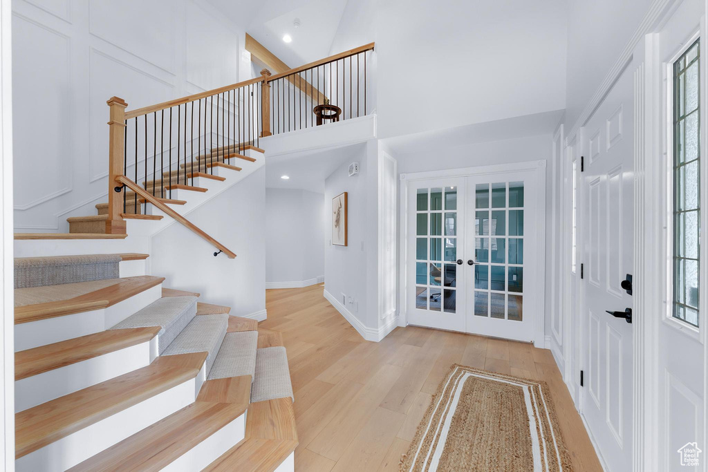 Entryway with french doors, wood finished floors, stairs, a high ceiling, and baseboards
