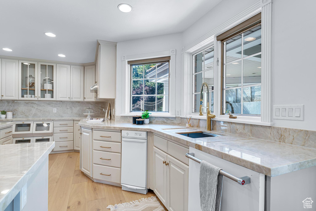 Kitchen featuring a sink, dishwasher, recessed lighting, light wood-style floors, and white cabinets