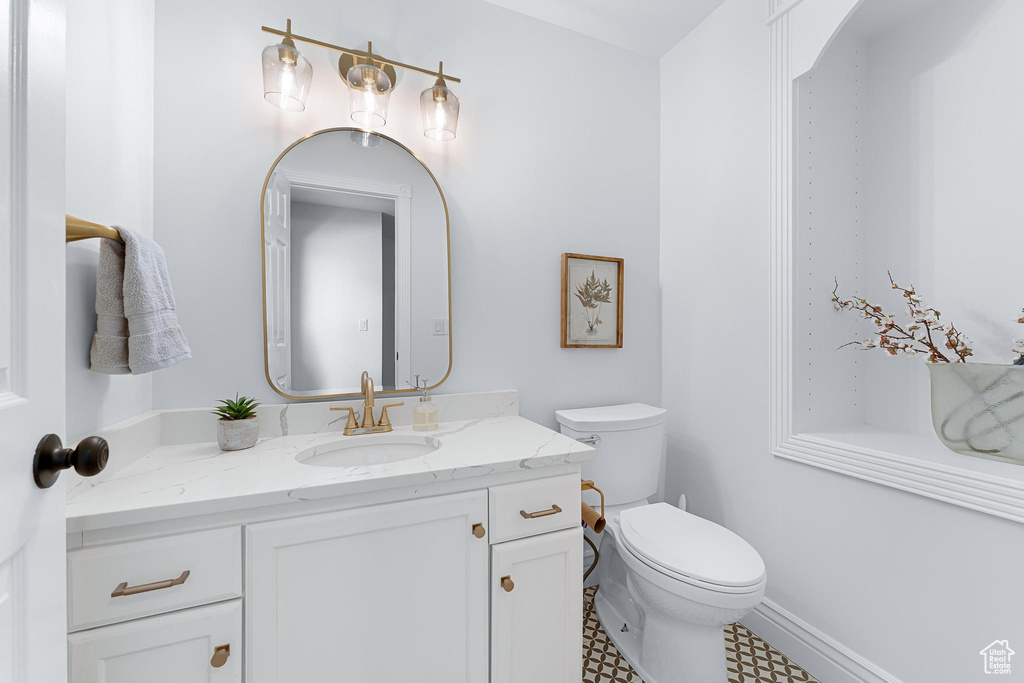 Half bath featuring vanity, toilet, and baseboards