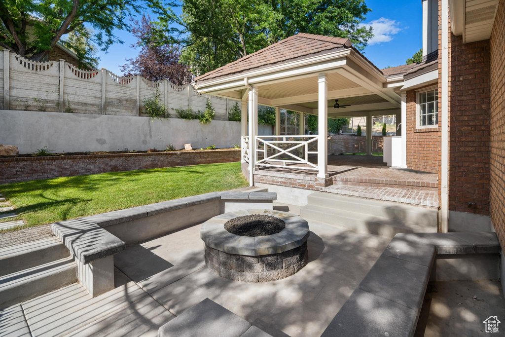Covered porch featuring an outdoor fire pit, ceiling fan, and a patio