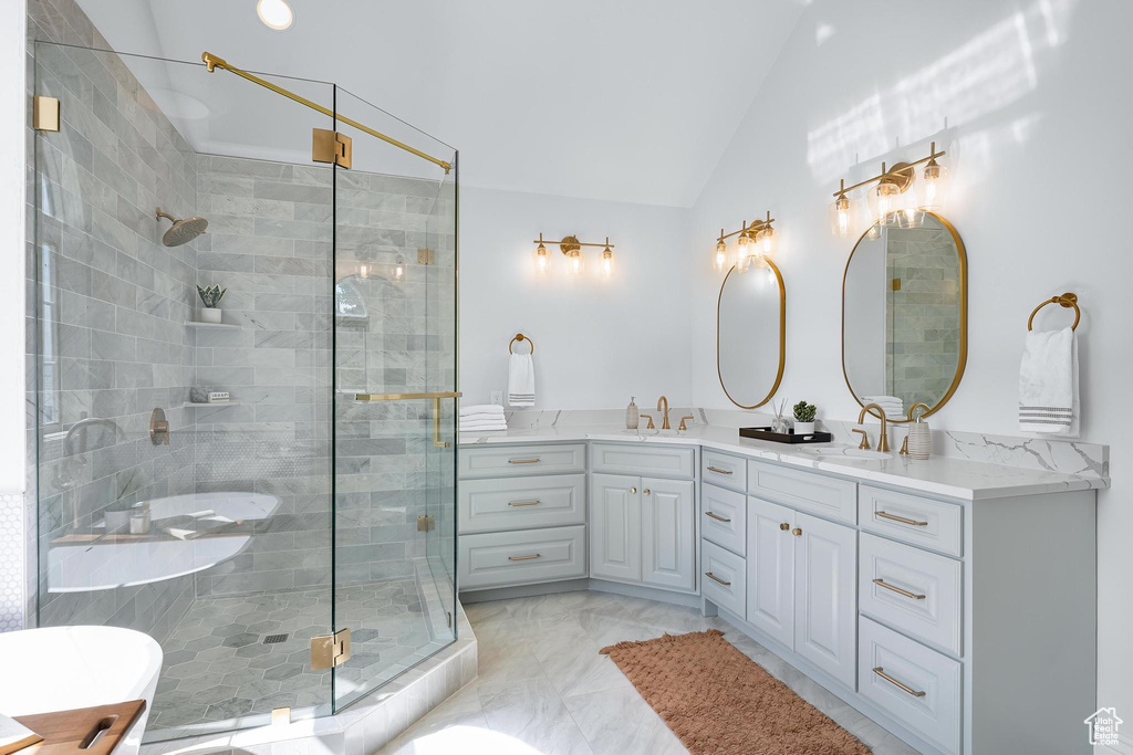 Bathroom with vaulted ceiling, double vanity, a shower stall, a freestanding tub, and marble finish floors