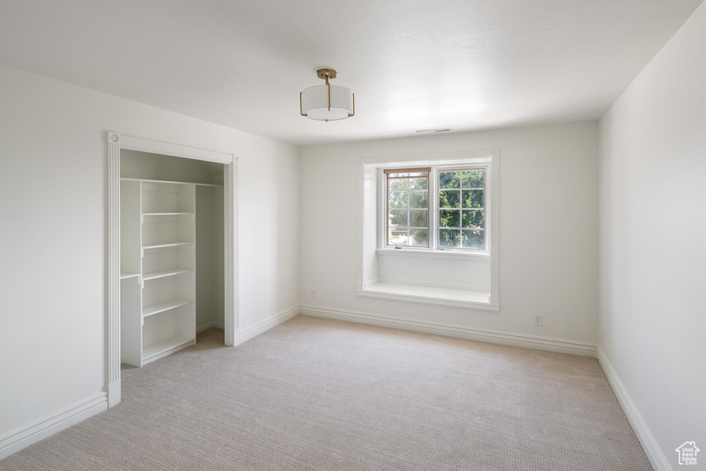 Unfurnished bedroom featuring light carpet, baseboards, and a closet