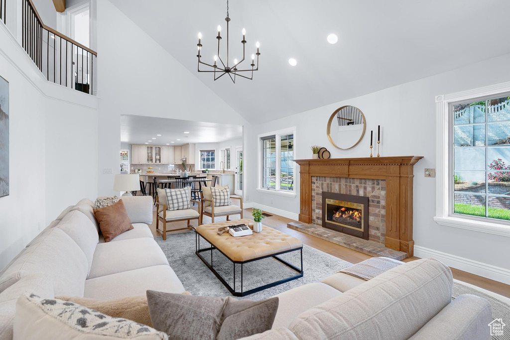 Living room with a chandelier, baseboards, light wood-style floors, high vaulted ceiling, and recessed lighting