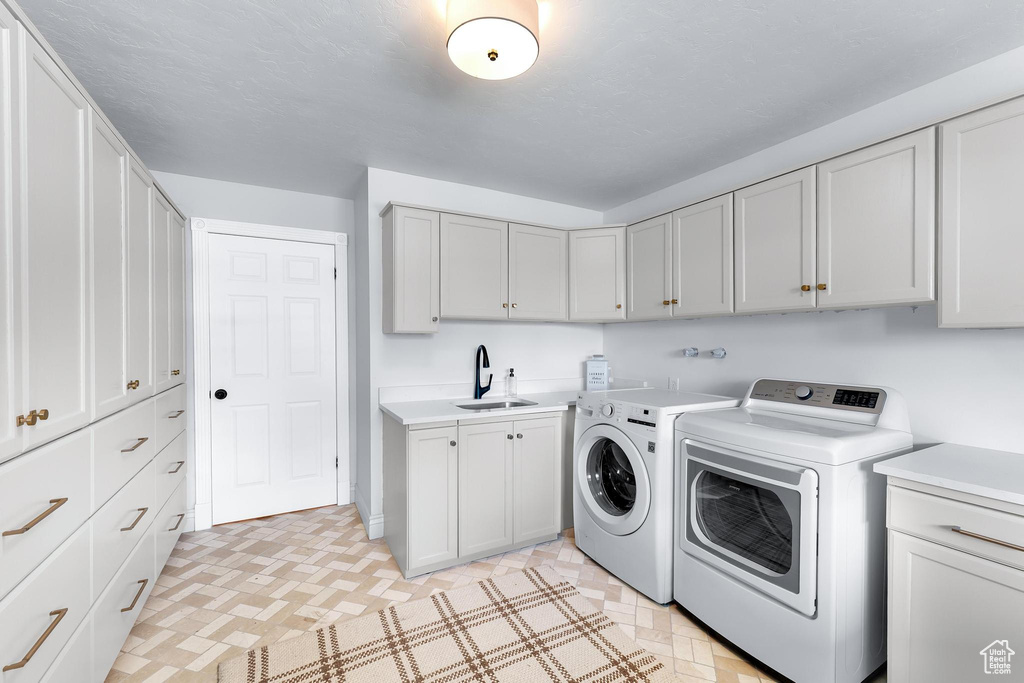 Laundry room with separate washer and dryer, cabinet space, and light floors
